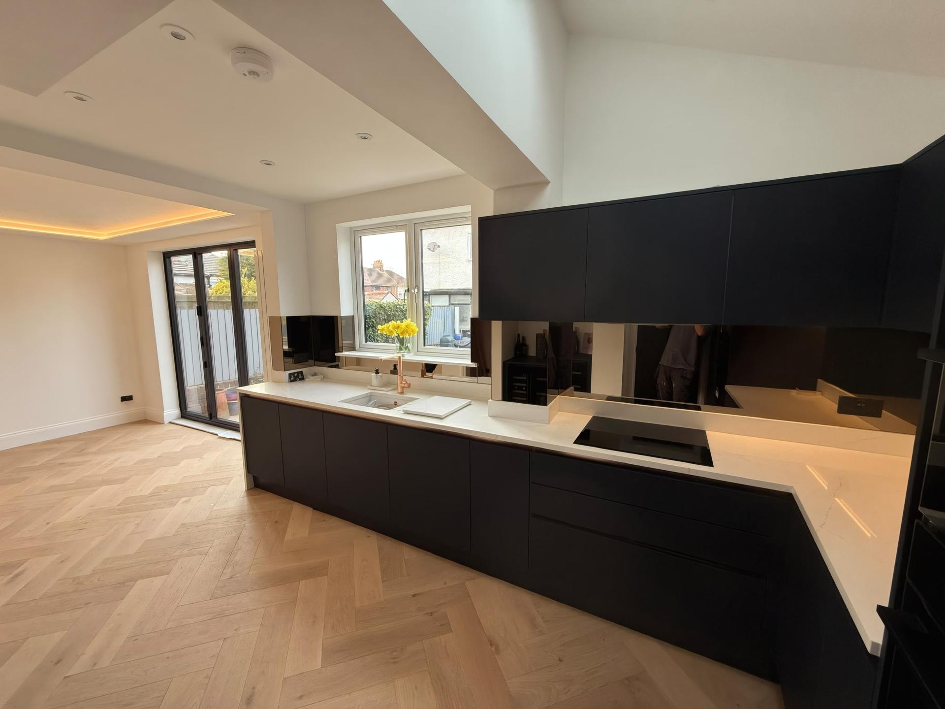 Handleless kitchen with quad integrated ovens and slatted oak ceiling bulkhead in Crosby