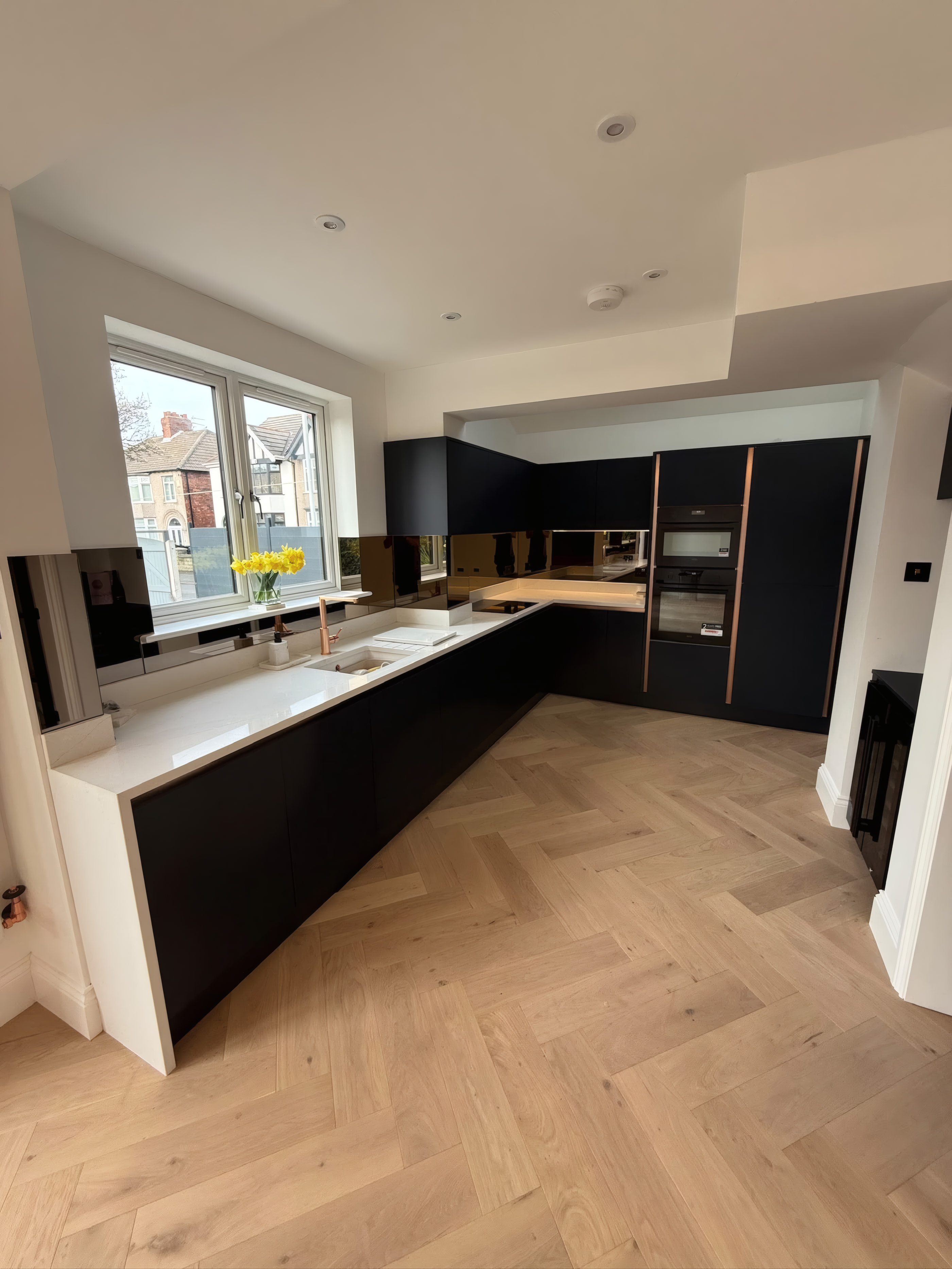 Detail of central kitchen island and acoustic oak slatted ceiling feature with LED lighting
