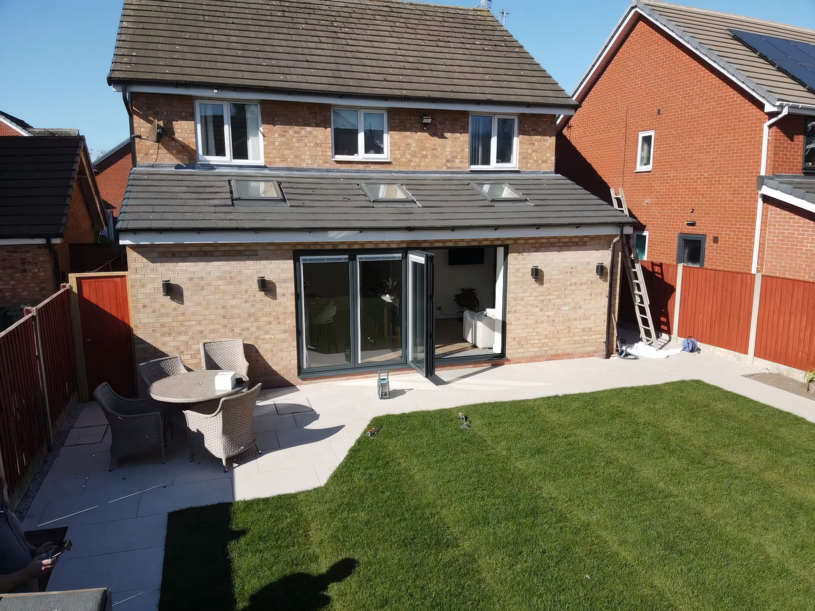 Red brick pitched roof rear extension with three Velux windows and black bi fold doors
