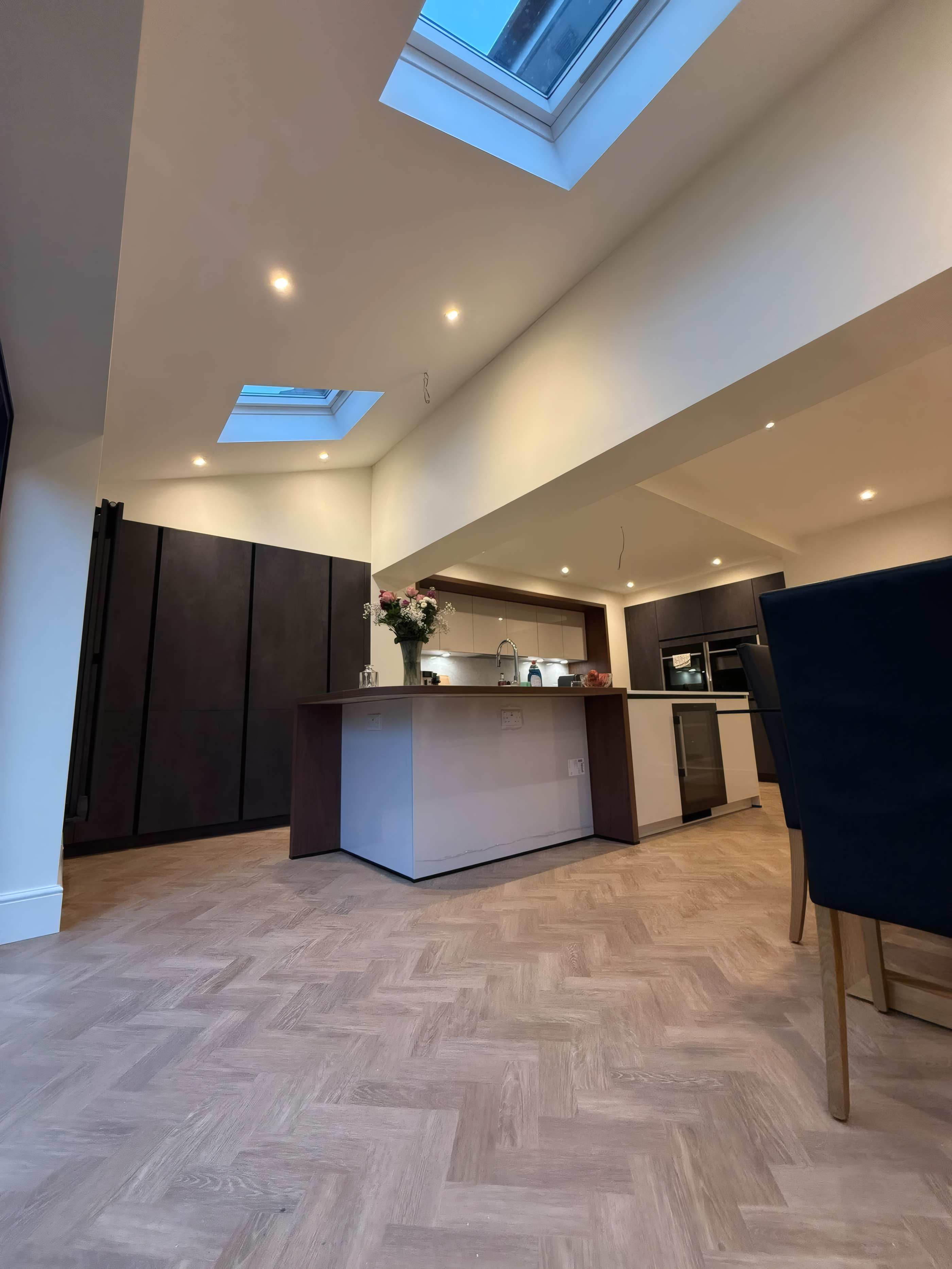 Detail of kitchen island with solid walnut breakfast bar and herringbone oak flooring