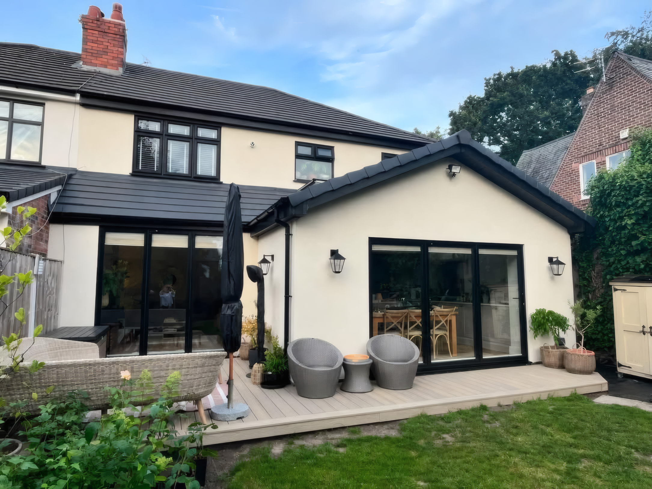 Rear house extension exterior with twin black bi fold doors and composite decking